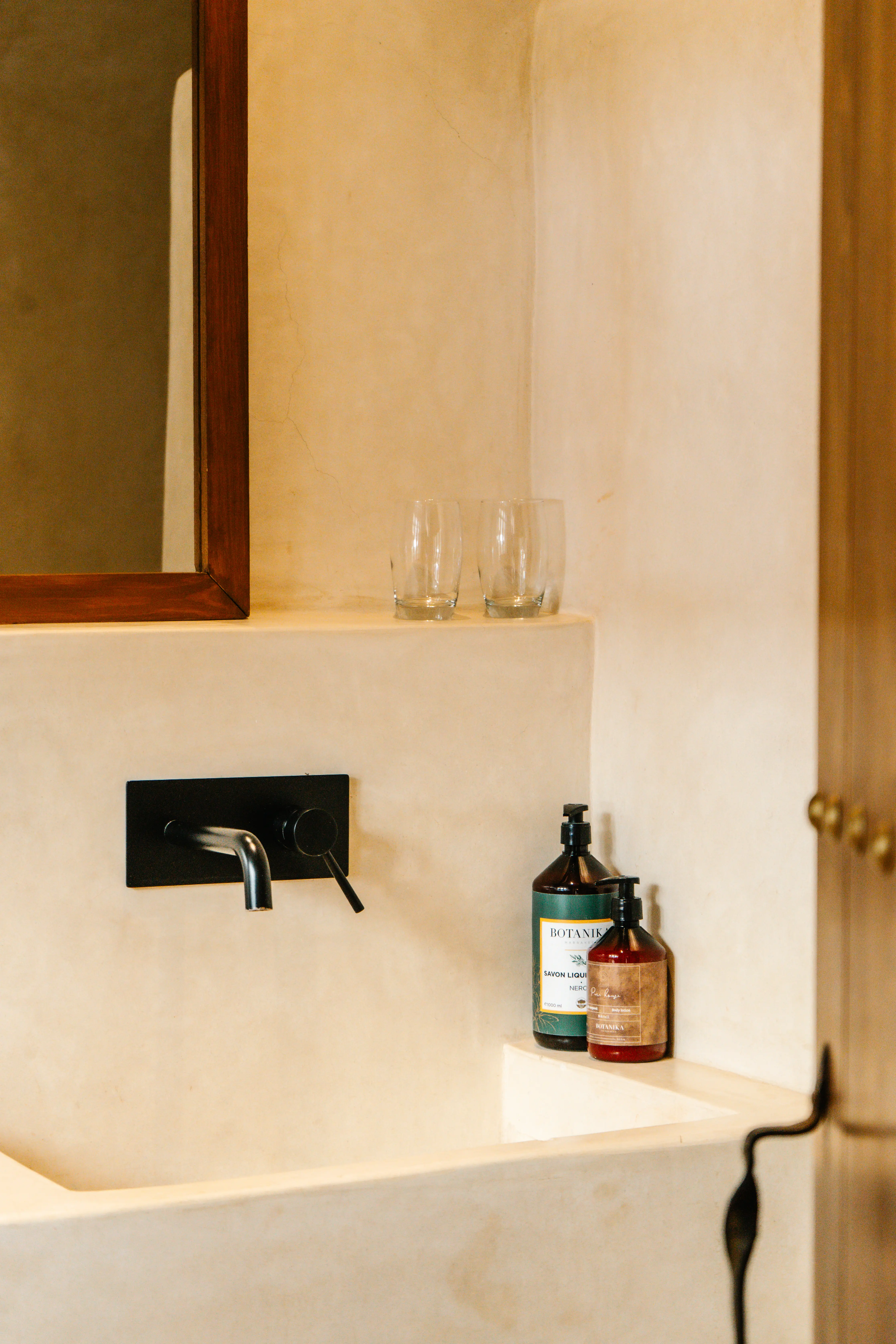 Clean, modern ensuite bathroom with traditional Moroccan tadelakt finishes and luxury wellness products in a boutique riad.